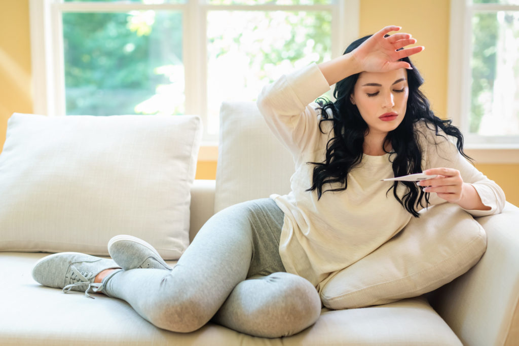 young woman taking temperature from illness symptom